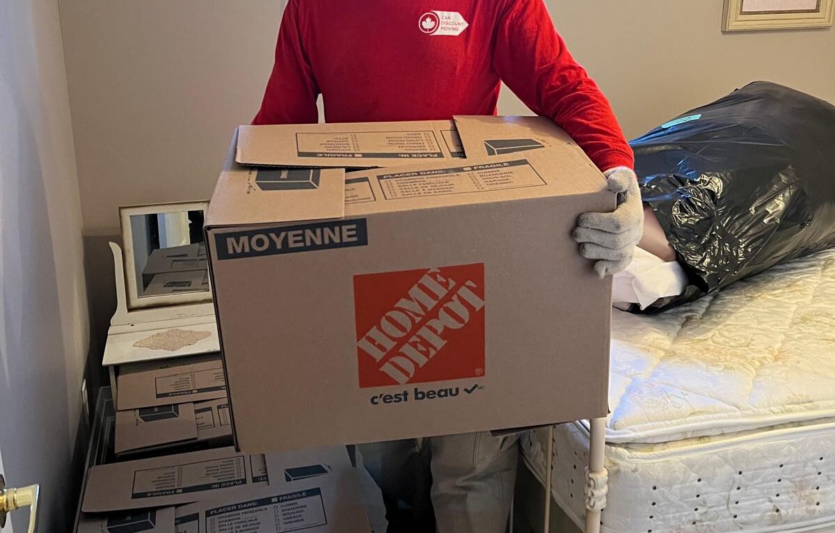 Professional moving team member carrying boxes and arranging furniture inside a home during a moving day