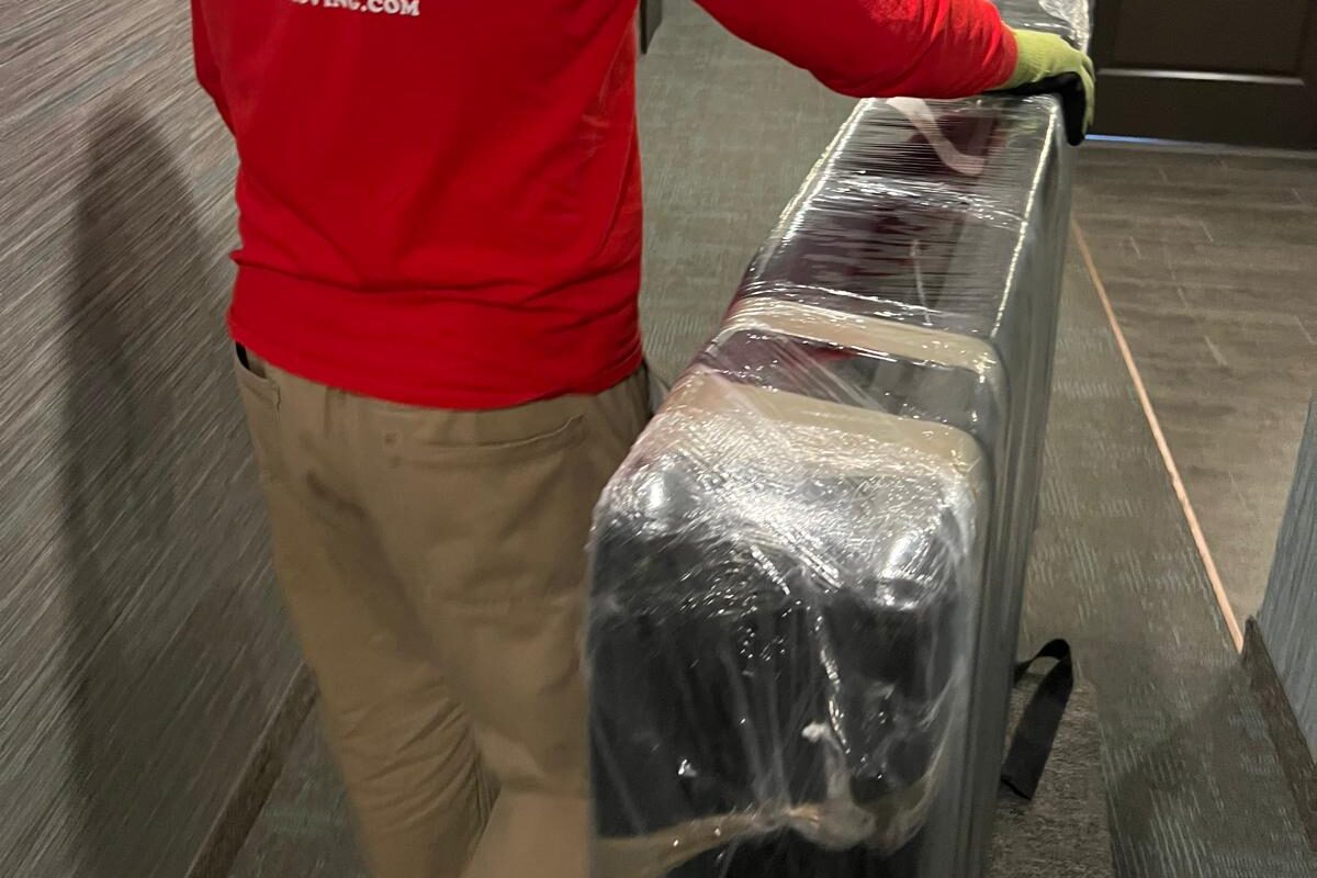 Moving to Mississauga? Here's Everything You Need to Know 1 Mover carrying heavy boxes and wrapping furniture during a residential move with a trusted moving company in Mississauga Ontario.